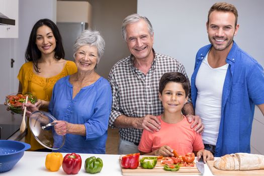 Portrait of happy family in the kitchen chopping vegetables at home