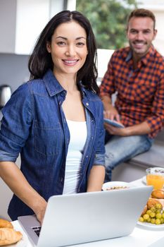 Portrait of couple using laptop and digital tablet in the kitchen