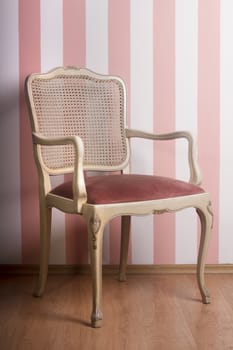 Vintage wooden chair against a pink stripe interior wall