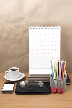 office desk : coffee with phone,wallet,calendar,color pencil box,stack of book,heart,eyeglasses on wood background