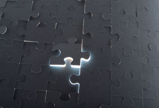 Grey puzzle background with flying piece, close up view