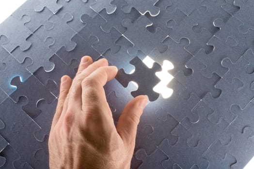 Man holding puzzle piece making puzzle, close up view