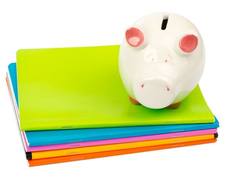 Piggy bank on pile of copybooks on isolated white background, side view