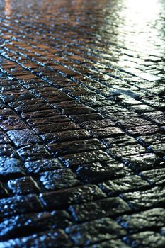 Night city. Closeup of wet cobblestone at night after rain