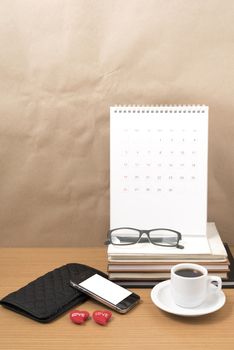 office desk : coffee with phone,wallet,calendar,heart,stack of book,eyeglasses on wood background