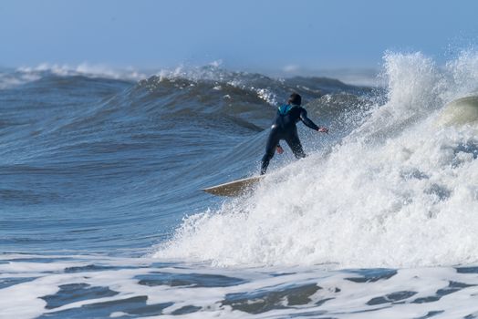 Surfer in action on the ocean waves on a sunny day.