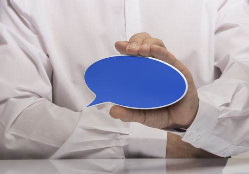 Image of a man hand holding empty blue speech balloon, white shirt and reflexion. 