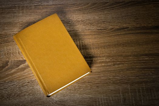 Yellow book on the wooden scratched table