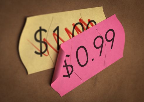 Psychological pricing printed on a pink label over a normal price. Concept image for illustration of prices psychological impact.
