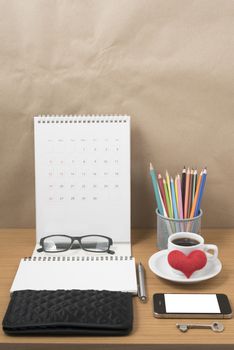office desk : coffee with phone,wallet,calendar,heart,notepad,eyeglasses,color pencil box,key on wood background