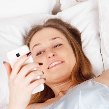 Young woman using smart phone on the bed