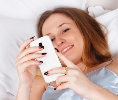 Young woman using smart phone on the bed