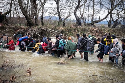 GREECE, Idomeni: Migrants and refugee cross a surging river on their way to Macedonia from a makeshift camp at the Greek-Macedonian border, near the Greek village of Idomeni on March 14, 2016, where thousands of them are stranded by the Balkan border blockade. More than 14,000 people are stuck on the Greek side of the border in an overcrowded camp at Idomeni after the main migrant route to western Europe through the Balkans was effectively shut down last week.