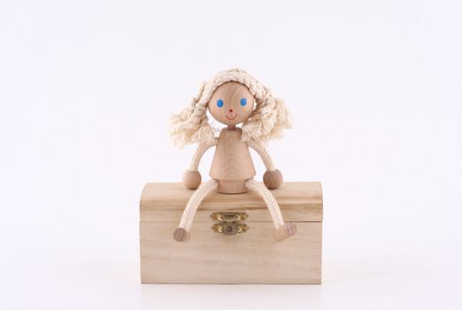 hand made wooden girl sitting on a wooden chest