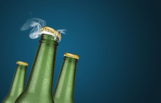 Horizontal photo of three green cold beer bottles with water drops and golden cap open on blue background