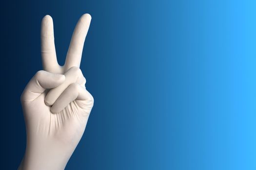 Hand with a white surgical glove showing the victory sign against a blue background