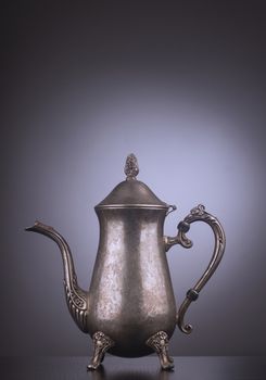 Silver vintage tea kettle with engravings on gray background