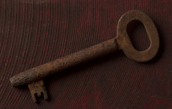 Old rusty key on wooden background