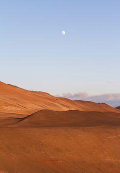 Vertical view of ash volcanic mountains with blue sky and moon above near Myvatn baths in Iceland