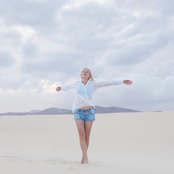 Relaxed woman enjoying freedom feeling happy at beach in the morning. Serene relaxing woman in pure happiness and elated enjoyment with arms outstretched. Copy space.