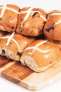 Hot cross buns on a timber board with a white background.