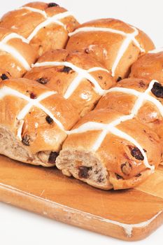 Hot cross buns on a timber board with a white background.