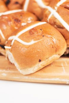 Hot cross buns on a timber board with a white background.