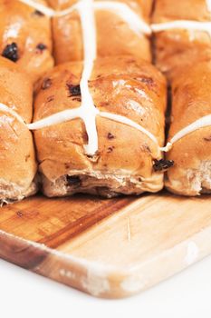 Hot cross buns on a timber board with a white background.