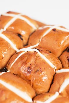 Hot cross buns on a timber board with a white background.