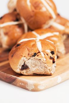 Hot cross buns on a timber board with a white background.