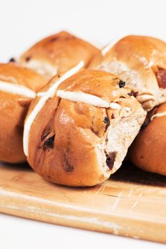 Hot cross buns on a timber board with a white background.