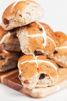 Hot cross buns on a timber board with a white background.