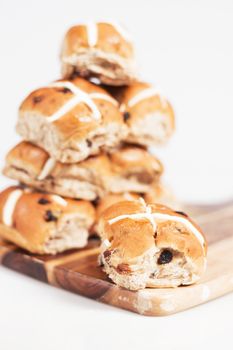 Hot cross buns on a timber board with a white background.