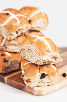 Hot cross buns on a timber board with a white background.
