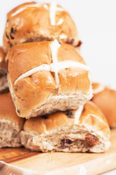 Hot cross buns on a timber board with a white background.