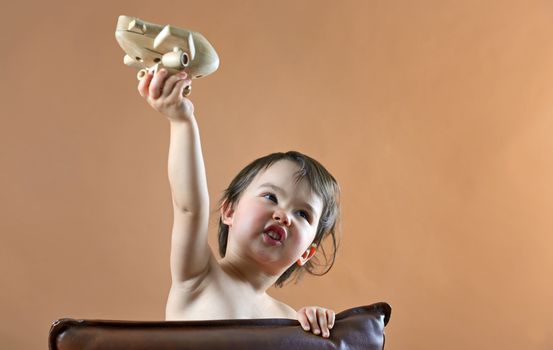 happy child girl playing with toy airplane in studio