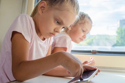 Two girls sisters sitting in the train playing phone