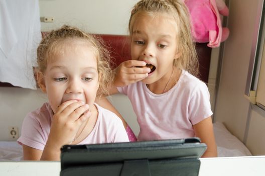 Two girls sisters sitting in the train watching cartoon Tablet PC
