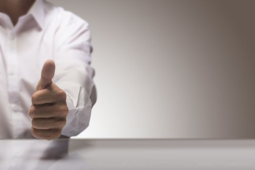 Man with one thumb up at the background of a glossy table and copy space on the right, concept image for illustration of excellent quality service.