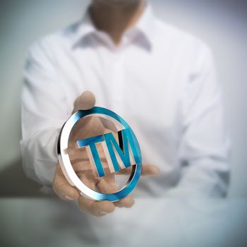 Man holding metallic trademark symbol. Concept image for illustration of intellectual property or protection of products or services.