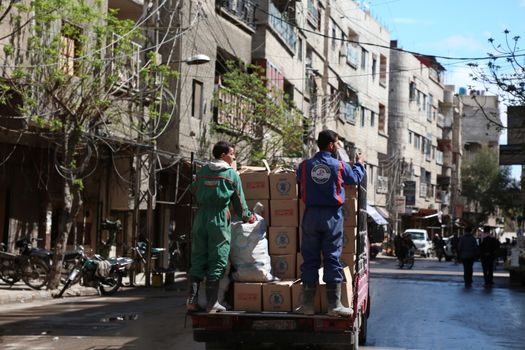 SYRIA, Saqba: Syrian Red Crescent staff survey the delivery of humanitarian aid at a warehouse in Saqba, in the rebel-held Eastern Ghouta area, southern Syria, on the outskirts of the capital Damascus on March 15, 2016 during an operation in cooperation with the UN to deliver aid to thousands of besieged Syrians. UN aid convoys head to two Syrian towns besieged by government forces to deliver life-saving food and medicine to some 30,000 people, a UN spokesman said. 
