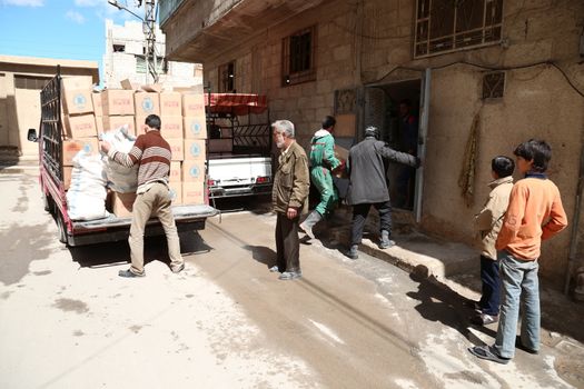 SYRIA, Saqba: Syrian Red Crescent staff survey the delivery of humanitarian aid at a warehouse in Saqba, in the rebel-held Eastern Ghouta area, southern Syria, on the outskirts of the capital Damascus on March 15, 2016 during an operation in cooperation with the UN to deliver aid to thousands of besieged Syrians. UN aid convoys head to two Syrian towns besieged by government forces to deliver life-saving food and medicine to some 30,000 people, a UN spokesman said. 