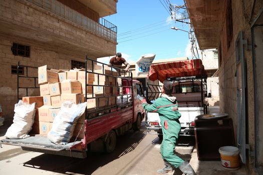 SYRIA, Saqba: A man carries a sack of wheat as Syrian Red Crescent staff survey the delivery of humanitarian aid at a warehouse in Saqba, in the rebel-held Eastern Ghouta area, southern Syria, on the outskirts of the capital Damascus on March 15, 2016 during an operation in cooperation with the UN to deliver aid to thousands of besieged Syrians. UN aid convoys head to two Syrian towns besieged by government forces to deliver life-saving food and medicine to some 30,000 people, a UN spokesman said. 