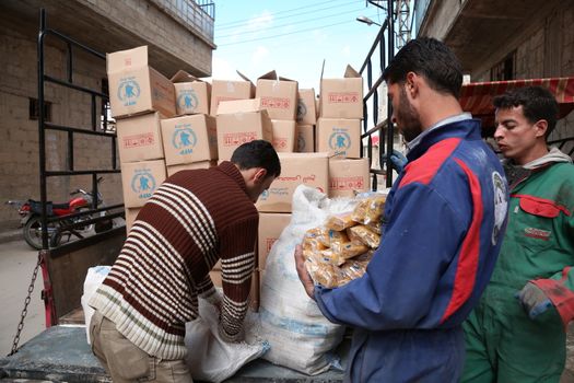 SYRIA, Saqba: Syrian Red Crescent staff survey the delivery of humanitarian aid at a warehouse in Saqba, in the rebel-held Eastern Ghouta area, southern Syria, on the outskirts of the capital Damascus on March 15, 2016 during an operation in cooperation with the UN to deliver aid to thousands of besieged Syrians. UN aid convoys head to two Syrian towns besieged by government forces to deliver life-saving food and medicine to some 30,000 people, a UN spokesman said. 