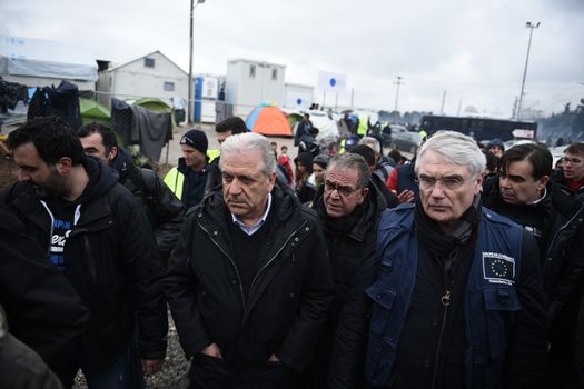 GREECE, Idomeni: Dimitris Avramopoulos, European commissioner for migration (C) walks along the railway tracks next to tents at the Idomeni refugee camp on the Greek Macedonia border on March 15, 2016 in Idomeni, Greece. Yesterday, an attempt by some of the residents of the camp to cross the border to Macedonia was thwarted by Macedonian security forces who returned the migrants to Greece. The decision by Macedonia to close its border to migrants last week has left thousands of people stranded at the Greek transit camp. The closure, following the lead taken by neighbouring countries, has effectively sealed the so-called western Balkan route, the main migration route which has been used by hundreds of thousands of migrants to reach countries in western Europe, such as Germany. Humanitarian workers have described the conditions at the camp as desperate, which has been made much worse by recent spells of heavy rain.