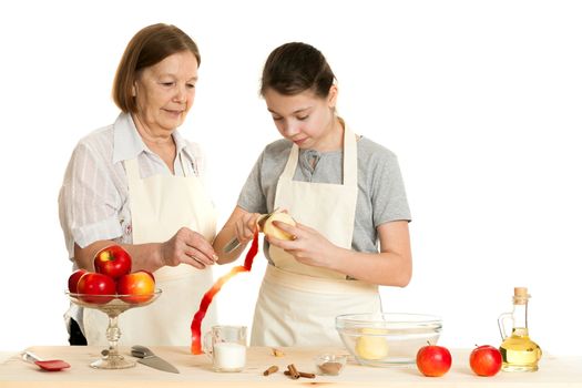 the grandmother teaches the granddaughter to cut off a peel from apple on a white background
