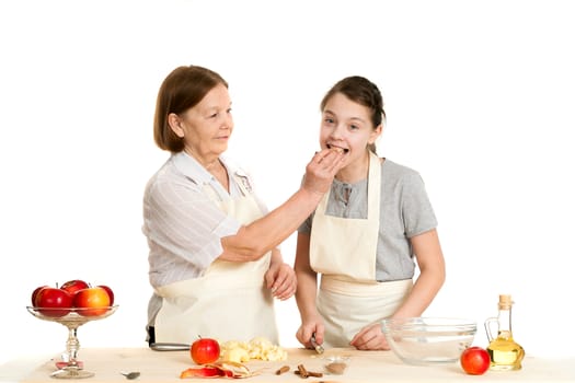 the grandmother and the granddaughter treat each other with apple pieces on a white background