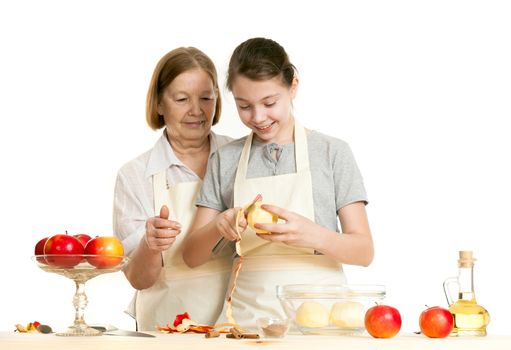 the grandmother teaches the granddaughter to cut off a peel from apple on a white background