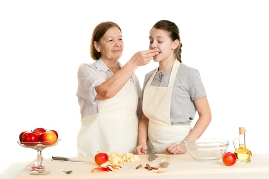 the grandmother and the granddaughter treat each other with apple pieces on a white background