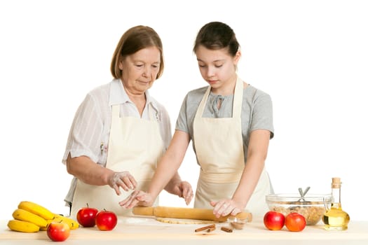 the grandmother and the granddaughter roll dough with a rolling pin for pie on a white background